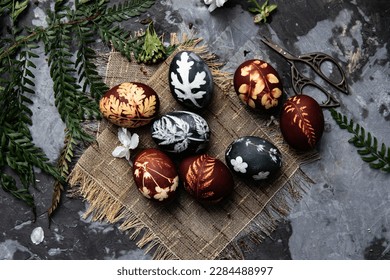 Easter eggs dyed with natural ingredients like cabbage, onion peel, hibiscus tea carcade on rustic wooden tray and craft paper.