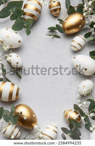 Easter eggs forming a frame with eucalyptus leaves and white flowers on a gray background