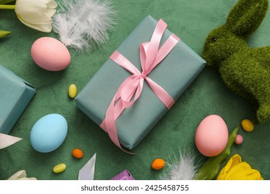 Easter eggs with gift box, tulip flowers and bunny on grunge green background