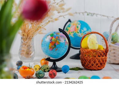 Easter Eggs And Globe On A White Wooden Background.