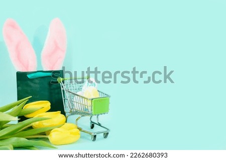 Easter eggs in a grocery basket on a blue background with yellow tulips and a paper bag. easter, shopping. High quality photo