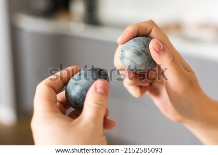 Easter eggs in hands. The custom is to beat Easter eggs against each other. Gaussian blurred background. Traditional Easter game with eggs knocking