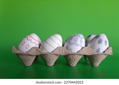Easter eggs for needlework. Preparing for holiday with children. Tray with decorative eggs on green background. Set for kid crafts in family and at school. Easter home decor.