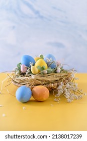Easter eggs in nest on blue background and yellow table.