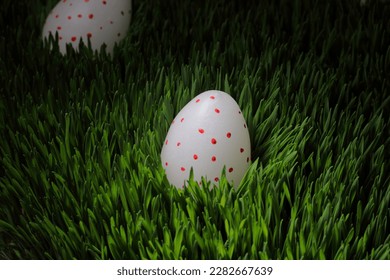 Easter eggs on green grass with dew drops, water drops, egg-shaped candles - Powered by Shutterstock