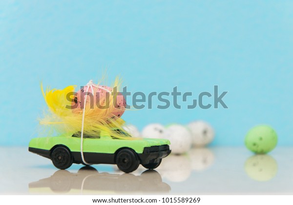 Easter eggs on\
a toy car of green color on a blue background.Delivery of products\
to Easter. The concept of\
Easter.