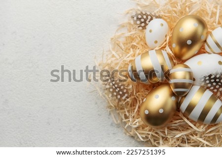 Easter eggs painted with gold paint on a straw background. Concept of Easter holidays. Festive background.