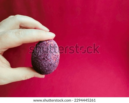 Easter eggs, painted in a new way, in red wine.the crystallization of the eggshell gives the product a shine in the candlelight.the color of the religious holiday is maroon-red.The hand taking the egg