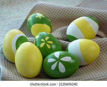 Easter Eggs Painted With Yellow And Green Paint Depicting Flowers And Stripes Lie On A Kitchen Towel. Preparation For Easter, Decor.