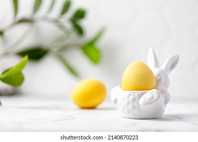 Easter eggs painted in yellow with turmeric for Easter. Yellow eggs in ceramic bunny. Greens