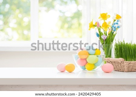 Easter eggs and spring flowers on white table over blurry kitchen window background