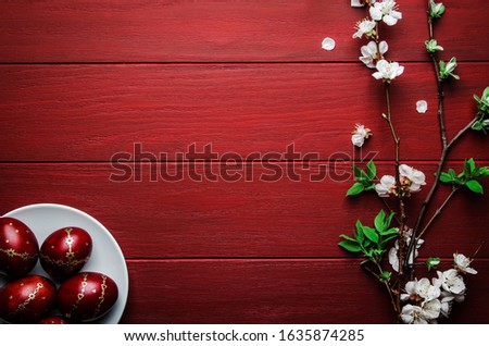 Easter eggs and spring white flowers on Easter red wood background with copy space