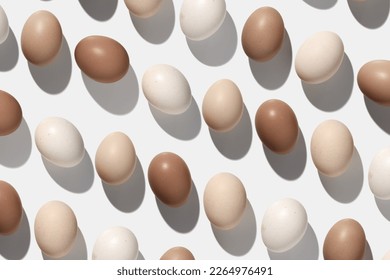 Easter eggs trend pattern, shadow at sunlight, white light background. Organic Chicken eggs with natural pastel colored eggshells, food Easter celebration concept, top view, trend aesthetic flat lay
