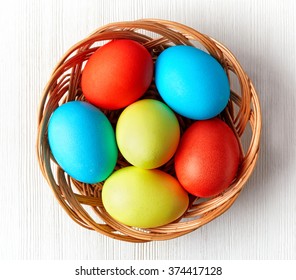 Easter Eggs In A Wicker Basket On White Background, Top View