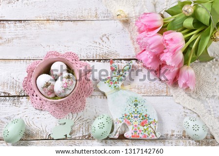 easter flat lay with bunch of pink tulips,painted eggs and decoupage bunny on white wooden background