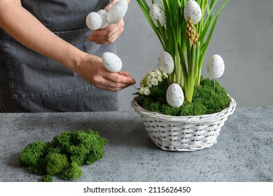 Easter floral DIY composition for table centerpiece with white eggs, moss and bunny. Close up. Woman make spring decor.