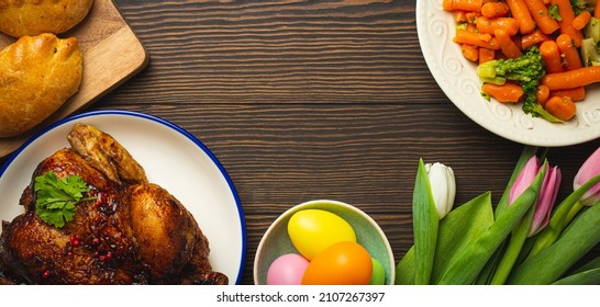 Easter Food On Dark Rustic Table: Pastel Colored Eggs, Roasted Chicken And Vegetables, Buns And Spring Flowers Tulips Top View Flay Lay, Easter Family Dinner Meal With Festive Dishes, Space For Text