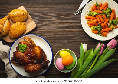 Easter Food On Dark Rustic Table: Pastel Colored Eggs, Roasted Chicken And Vegetables, Buns And Spring Flowers Tulips Top View Flay Lay, Easter Family Dinner Meal With Festive Dishes, Space For Text