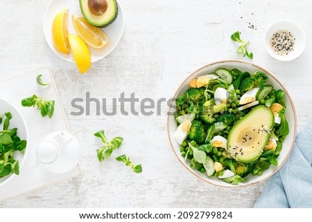 Easter fresh vegetable salad with boiled egg, broccoli, corn salad, green peas and avocado, top view