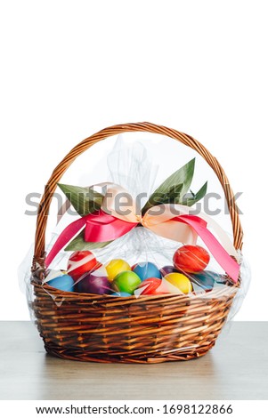 Easter gift basket with multicolor eggs, white background