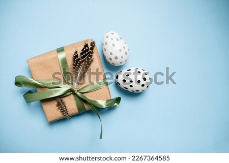 easter gift in eco package with decorative eggs on a blue background. top view. copy space.