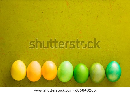 Easter green and yellow eggs on the old wooden background with free space for text