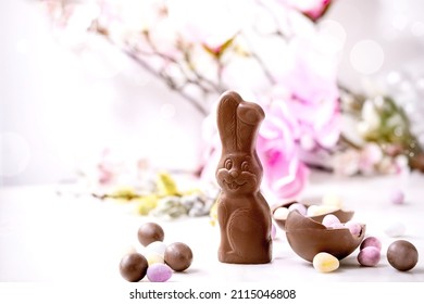 Easter greeting card with chocolate sweets rabbit, candies and eggs, spring blossom branches on white background. Easter treats, copy space - Powered by Shutterstock