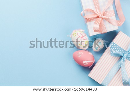Easter greeting card with gift boxes and colorful easter eggs on blue background. Top view flat lay with space for your greetings