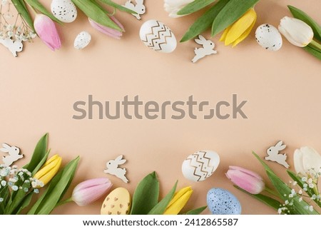 Easter happiness concept. Top view flat lay of painted eggs, fresh tulips, cute easter bunnies on beige background with marketing space