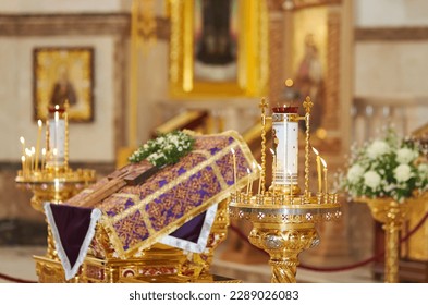 Easter holiday. Burning candles against the background of a cross in an Orthodox church decorated with flowers. Orthodox faith. Prayer to God