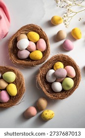 Easter holiday Spring background with mini eggs candy in nests over bright background. High quality photo