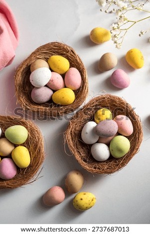 Easter holiday Spring background with mini eggs candy in nests over bright background. High quality photo
