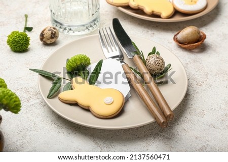 Easter holiday table setting with bunny cookie, quail eggs, and cutlery on a beige plate