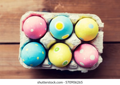 easter, holidays, tradition and object concept - close up of colored easter eggs in egg box or carton wooden surface