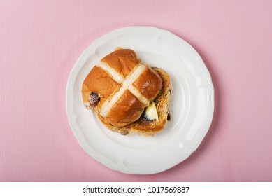 Easter Hot Cross Bun served with Butter on White Plate, Top View, Pastel Pink Background