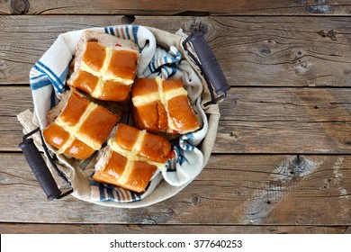 Easter Hot Cross Buns in a basket, downward view on a rustic wood background
