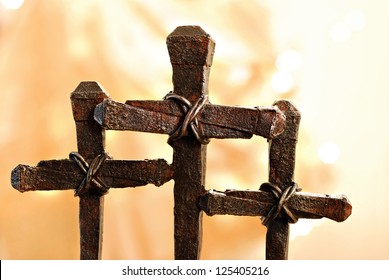 Easter image of rusty nail crosses with gold fabric and defocused lights as background.  Macro with shallow dof.