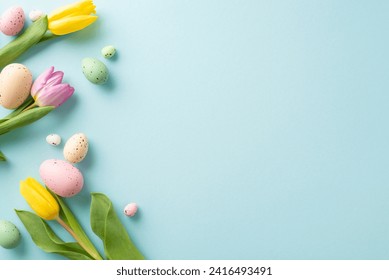 Easter Joy Composition: top view colorful eggs, and fresh tulips on a soft blue background. Ideal for greetings or promotions with space for text or ads