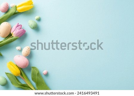 Easter Joy Composition: top view colorful eggs, and fresh tulips on a soft blue background. Ideal for greetings or promotions with space for text or ads