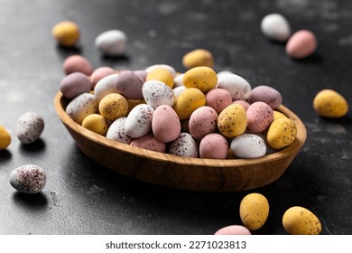Easter mini eggs, chocolate candy in wooden bowl