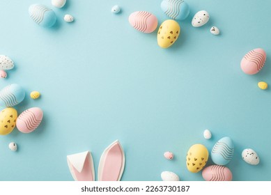 Easter party concept  Top view photo easter bunny ears white pink blue   yellow eggs isolated pastel blue background and copyspace in the middle