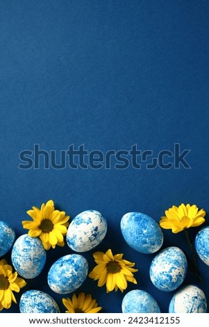 Easter poster, vertical banner design. Blue and white Easter eggs with yellow flowers on dark blue background. Top view. Flat lay.