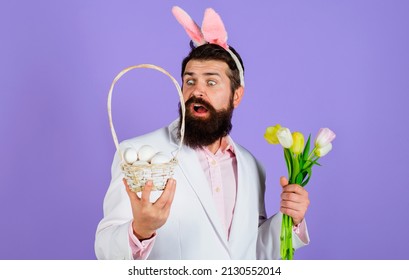 Easter. Rabbit Man In Bunny Ears With Flower. Bearded Male In Suit Holds Basket With Eggs.