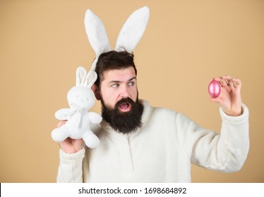 Easter rabbit. Man wearing rabbit suit. Funny bunny man soft ears. Easter activities concept. Weirdo concept. Celebrate Easter. Guy bearded hipster weird bunny with long white ears beige background.