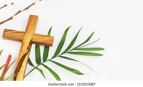Easter religion composition with wooden crucifixion, palm leaf, willow branch and red church candle on a white background with copy space. The concept of Holy Week, Palm Sunday and Lent - Shutterstock ID 2133315087
