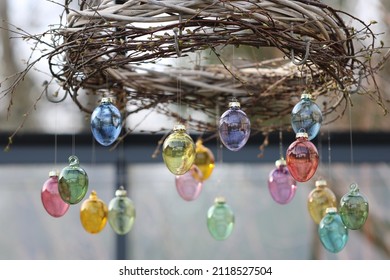 Easter scene with colourful glass eggs hand made wreath in greenhouse, springtime