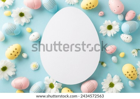 Easter setting idea: Overhead view of various eggs, and chamomile shoots on a tranquil blue surface, with an open egg-shaped outline for messages or advertising