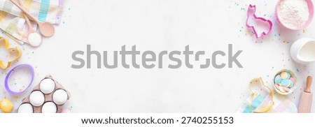 Easter or spring baking double border against a white marble banner background. Overhead view. Cookie cutters, eggs, and ingredients.