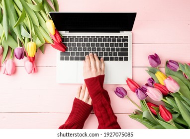Easter and spring concept. Woman hands typing on laptop keyboard. Feminime worlspace decorated with tulips