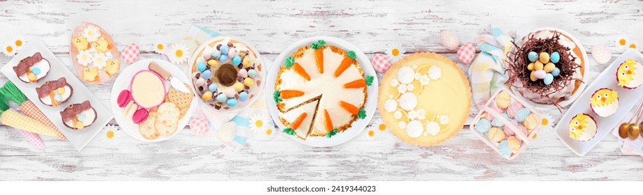 Easter or spring dessert food table scene. Top view over a white wood banner background. Lemon tart, cupcakes, Easter egg and carrot cakes and an assortment of sweets. - Powered by Shutterstock